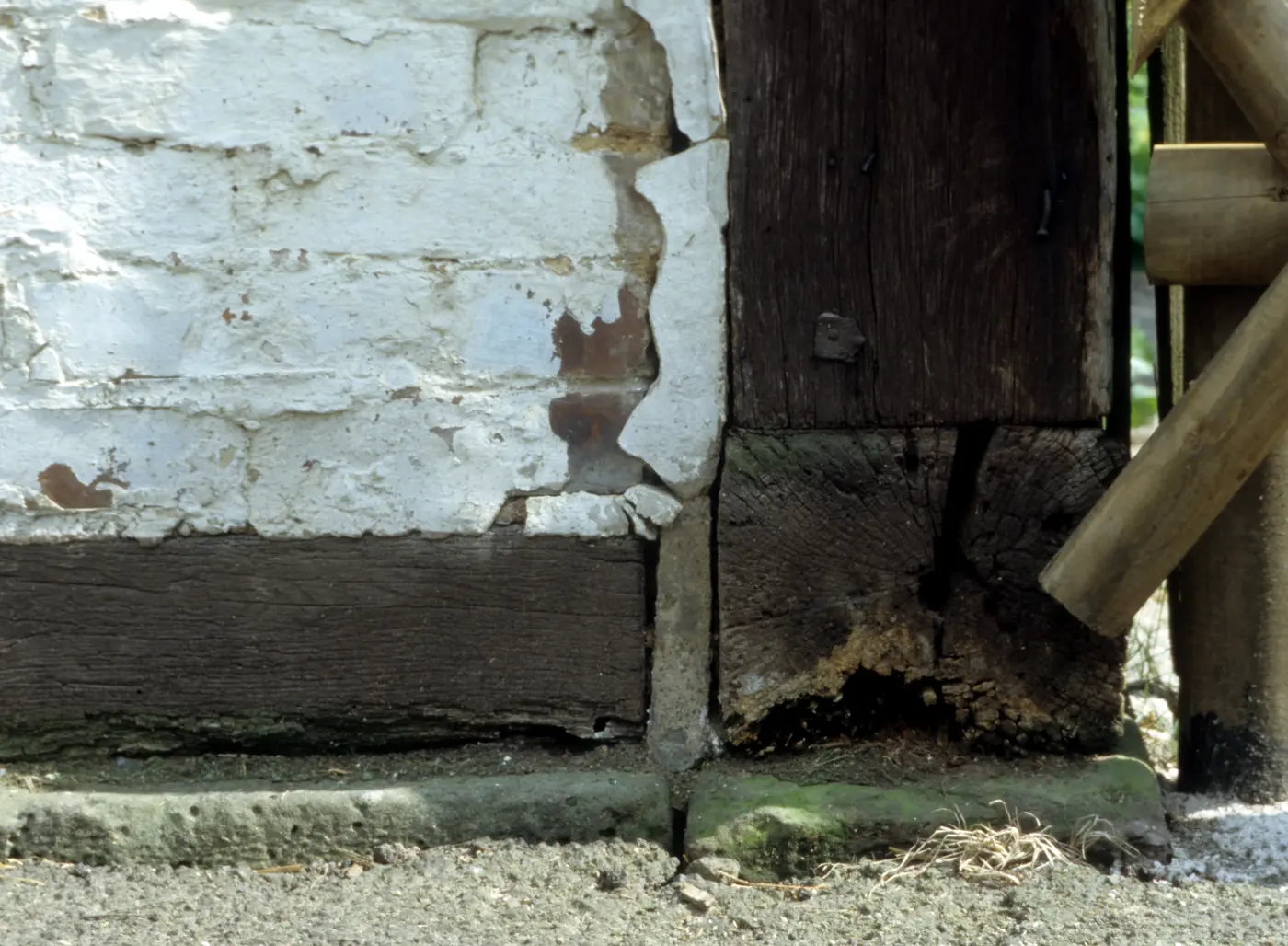 A decayed timber sill beam and post foot where a timber frame meets its masonry plinth.